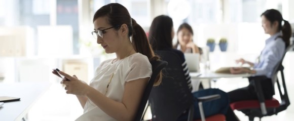 オフィスでスマホを見る女性