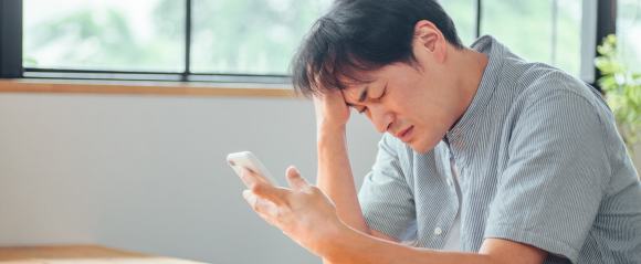 スマホを見て落ち込む男性のイメージ