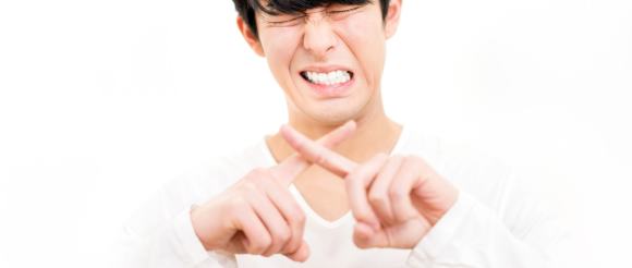 手でバツマークを作る男性のイメージ