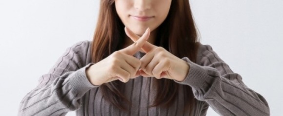 バツ印を見せる女性